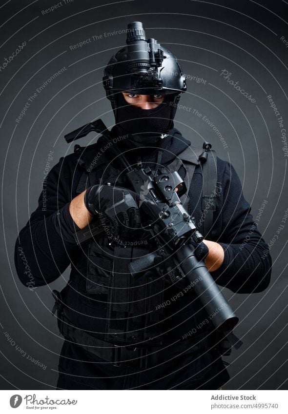 Attentive male warrior with rifle in dark room man combat squad concentrate focus weapon force danger serious fighter professional gear helmet gun safety lens