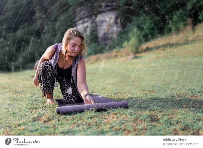 Female unrolling mat on lawn woman prepare session spirit meditate nature summer grass female adult practice zen shamanic healing wellbeing activity daytime