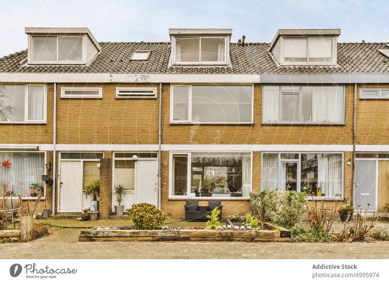 The facade of a brick building with wooden door house city entrance tree pavement front reflect architecture plant window balcony bicycle doorway home