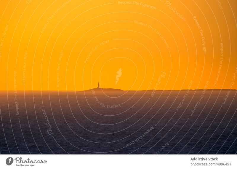 Remote beacon on island under orange sky lighthouse sunset sea evening sundown ocean twilight landscape minimal majestic water nature seascape dark dusk scenery