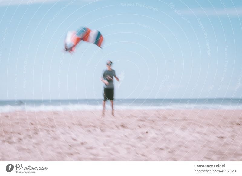 Boy with striped kite on the beach in ICM technique. Beach coastal strip Ocean Water Tourism seascape Landscape Vacation & Travel ICM technology hazy Unclear