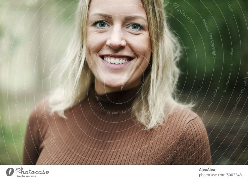 Young blonde woman with dimples stands in forest and smiles happily at camera Young woman Woman Blonde Feminine pretty fortunate Youth (Young adults) portrait