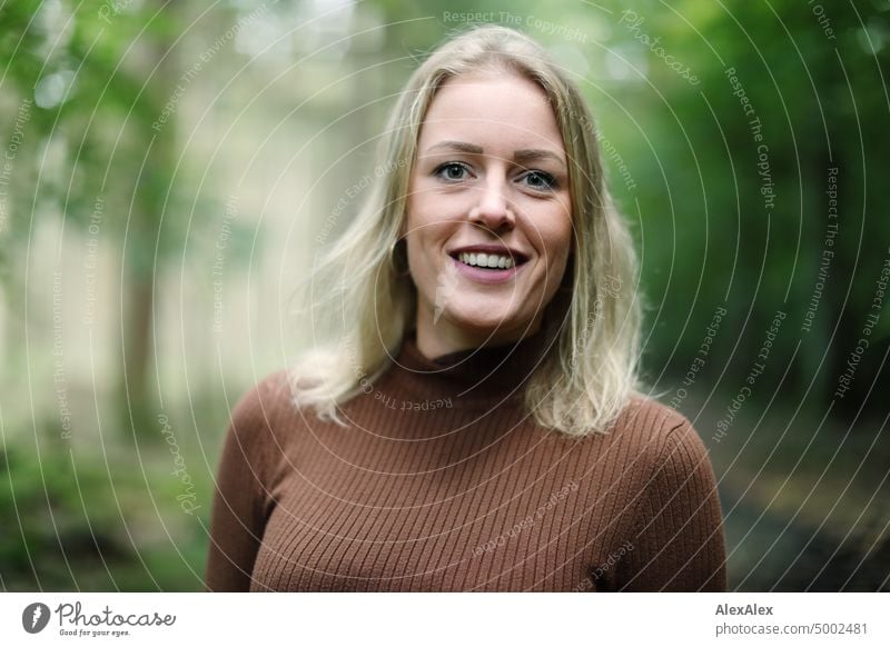 Young blonde woman with dimples stands in forest and smiles happily at camera Young woman Woman Blonde Feminine pretty fortunate Youth (Young adults) portrait