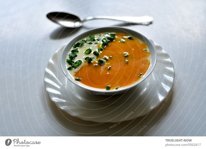 Pumpkin soup freshly pureed, plus some cream and spring onion greens finely chopped in white bowl on white plate and a soup spoon Soup Orange Cream White Chives