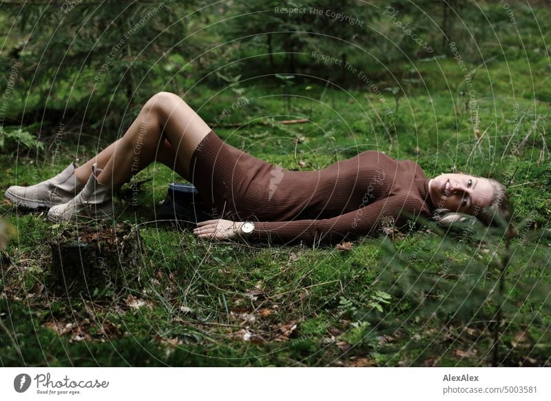 Young blonde woman lying on the moss in the forest and looking at the camera from the side Young woman Woman Blonde Feminine pretty fortunate