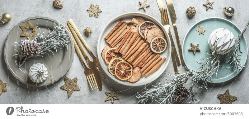 Christmas table setting with plates, golden cutlery, dried fruits and winter spices decoration, Christmas baubles and cookies. Top view. christmas