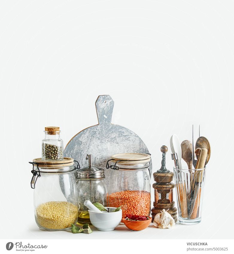 Sustainable kitchen setting with housekeeping jars and eco friendly kitchen utensils at white background. Front view. Modern still life sustainable front view