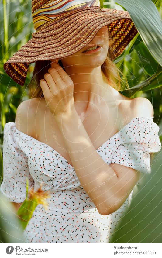 Sensual woman portrait in corn leaves. Face covered with hat, summer dress with plunging neckline sensual young green beautiful natural stylish face leaf