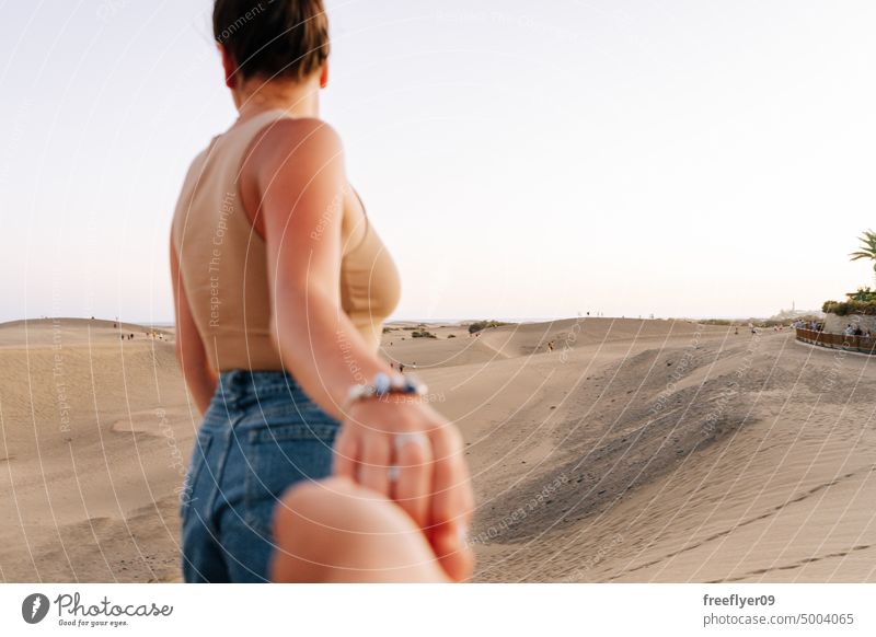 Tourist holding her partner's hand on the Maspalomas desert couple love honeymoon dune walking maspalomas sand Gran Canaria copy space Canary islands Spain