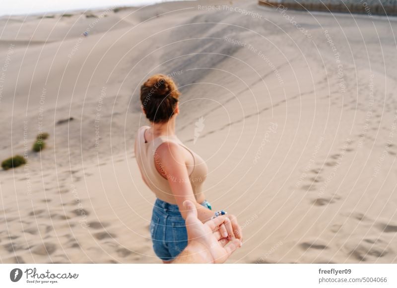 Tourist holding her partner's hand on the Maspalomas desert couple love honeymoon dune walking maspalomas sand Gran Canaria copy space Canary islands Spain