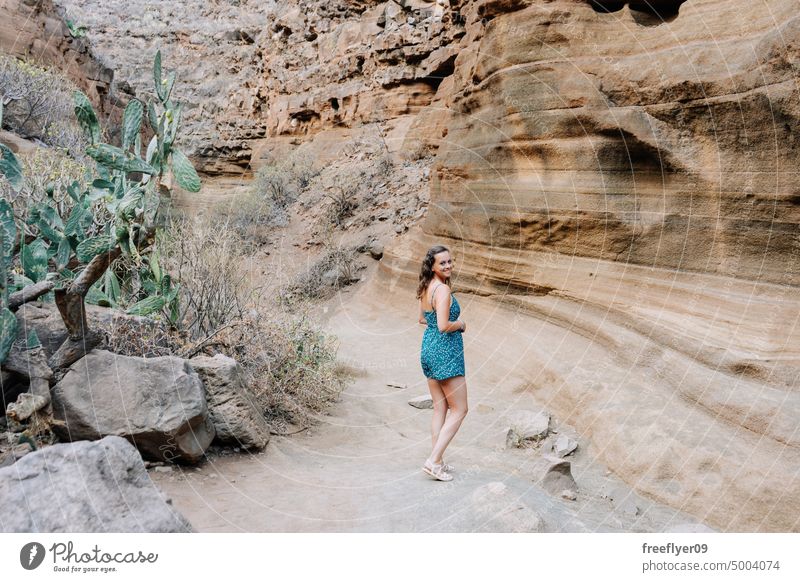 Woman walking by a dried canyon woman tourist nature visiting travel hiking blue copy space dress river desertic dry volcanic rocks dirt country tenerife rural