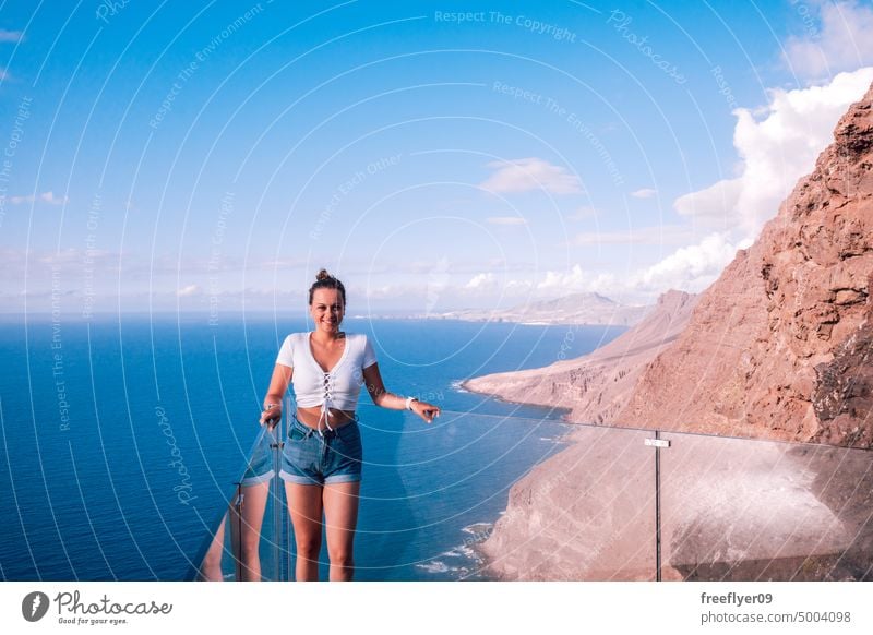 Tourist on a viewpoint against the ocean and volcanic cliffs lookout tourist young woman nature copy space blue hiking travel gran canaria canary islands spain