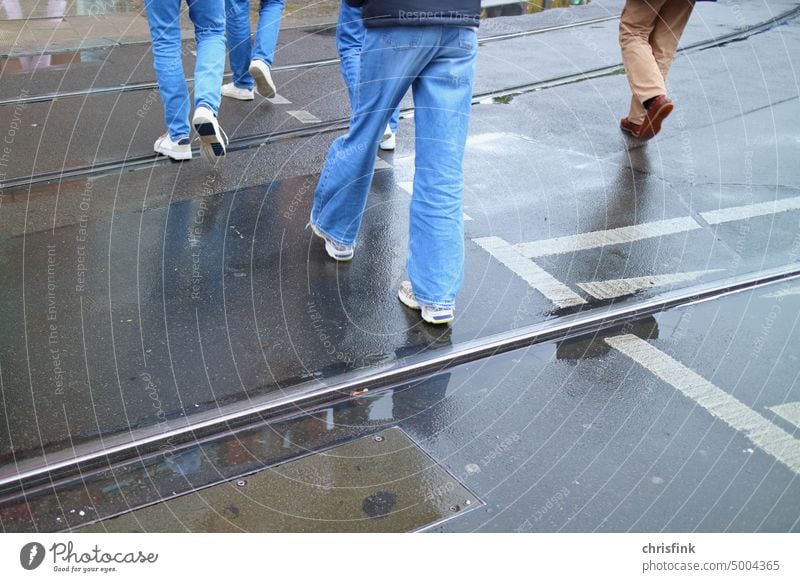 People run over wet road Street Wet Rain off Zebra crossing jeans feet Footwear Asphalt Stockings Legs Traffic light Road traffic Transport Puddle rail Railroad