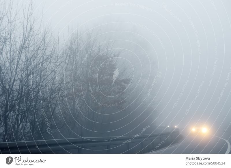 Thick fog on the highway in Europe on a winter day. The danger of driving of vehicles on roads in bad foggy weather. Insurance of safety of drivers and cars.