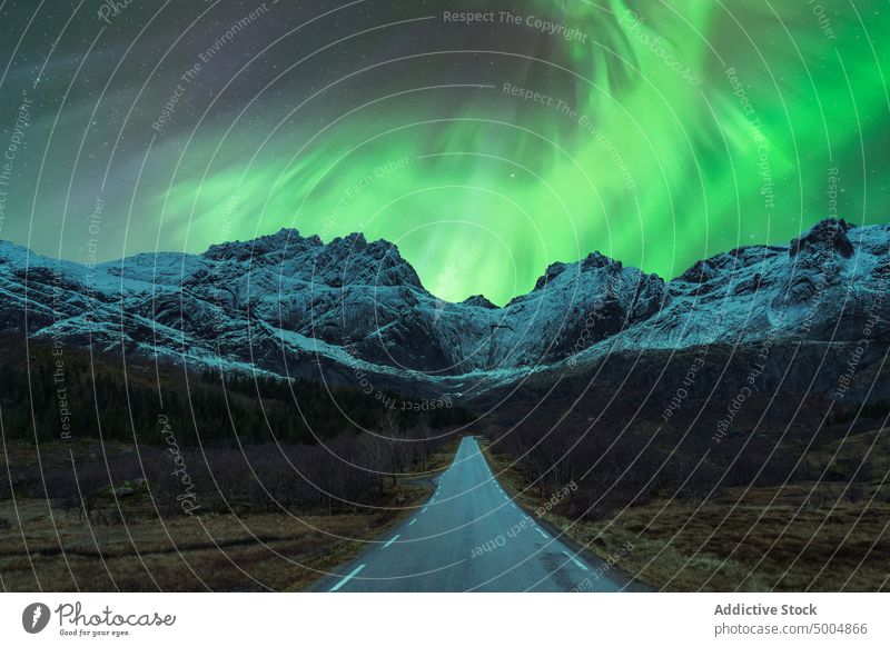 Car on road under green northern lights at night aurora borealis car mountain winter polar scenery sky shiny norway lofoten islands illuminate glow nature