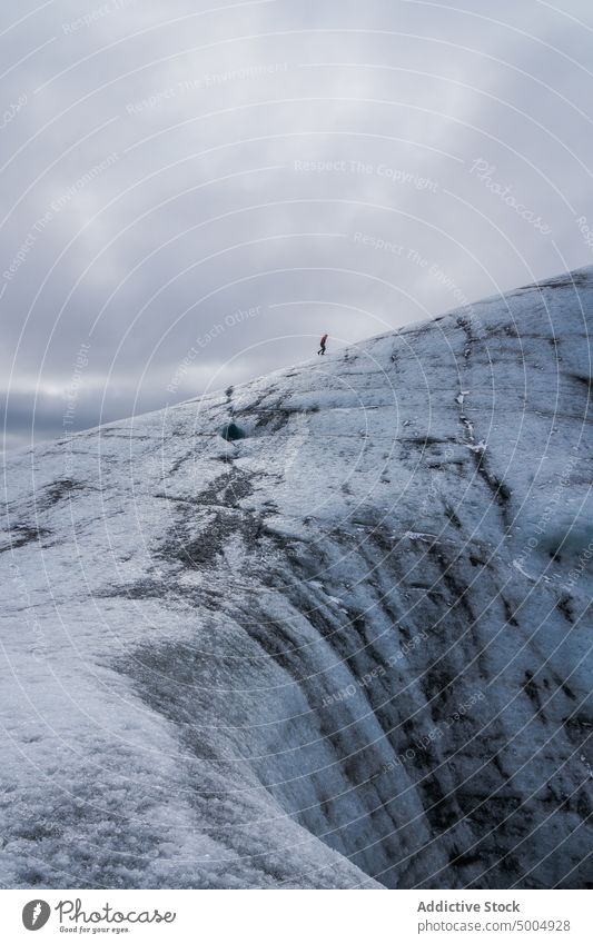 Ice formation with tourist in winter glacier ice traveler cold cloudy sky gray frozen iceland vatnajokull national park climate uneven overcast rough polar