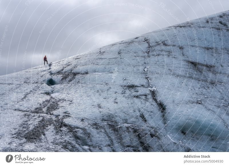 Ice formation with tourist in winter glacier ice traveler cold cloudy sky gray frozen iceland vatnajokull national park climate uneven overcast rough polar