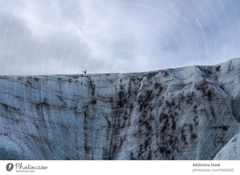 Traveler doing headstand on glacier traveler winter sky cloudy cold ice trick alpinism iceland vatnajokull national park weather season outerwear gray dull