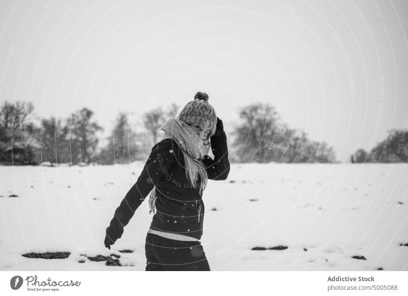 Positive woman walking on snowy terrain on gloomy winter day nature happy countryside positive snowfall meadow tree leafless female young warm clothes hat