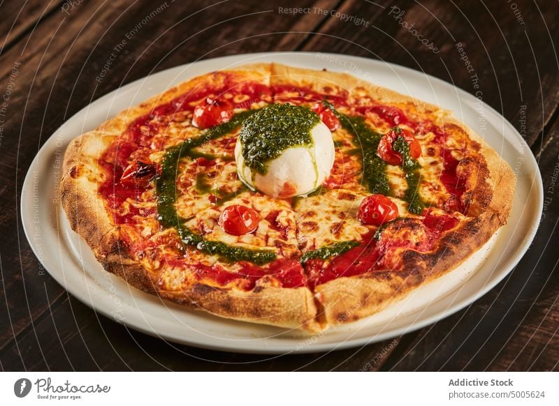 Pizza with mozzarella and pesto sauce pizza pizzeria plate cherry tomato parmesan cheese table dish serve lunch restaurant italian cuisine delicious food