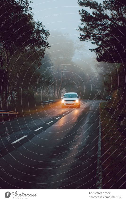 Close-up of a car alone on a road surrounded by trees and mountains forest nature landscape travel background outdoor beautiful woods countryside night danger