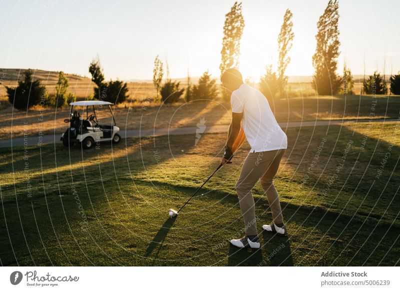 Golfer playing golf on course in countryside golfer sport prepare ball professional nature club man putter lean forward player field club and ball greenery