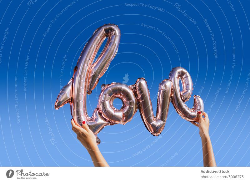 Love balloon against blue sky love inflatable summer hand woman word romantic happy silver shape cloudless concept show female joy festive decorative recreation