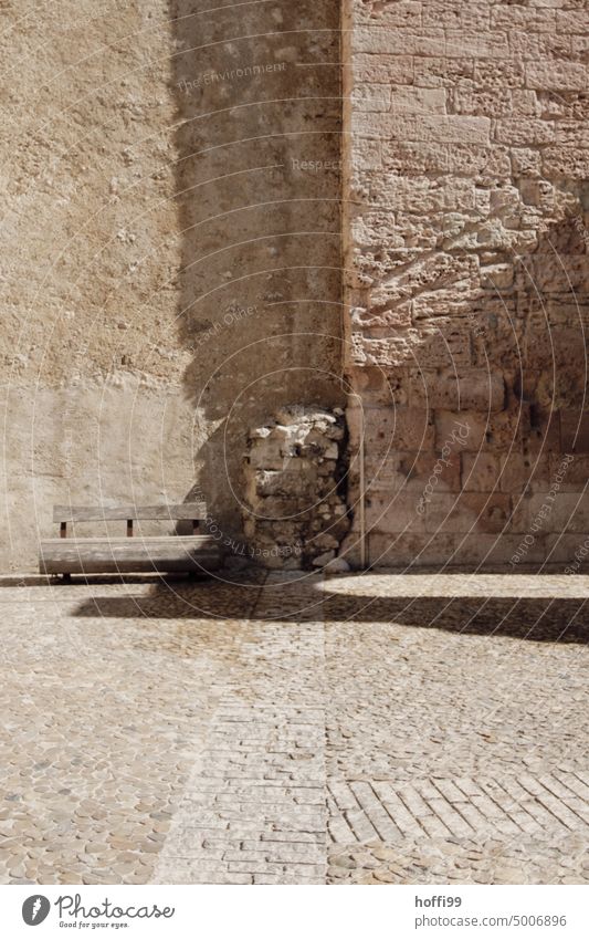 Bench in front of an old historical city wall in summer Mediterranean sunshine bench Sun Sunlight ardor Shadow City wall shadow cast Shadow play