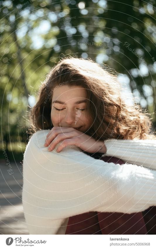 Smiling brunette woman with her eyes closed sitting in the park girl portrait cheerful nature outdoors adult outside attractive pretty smile cute young happy