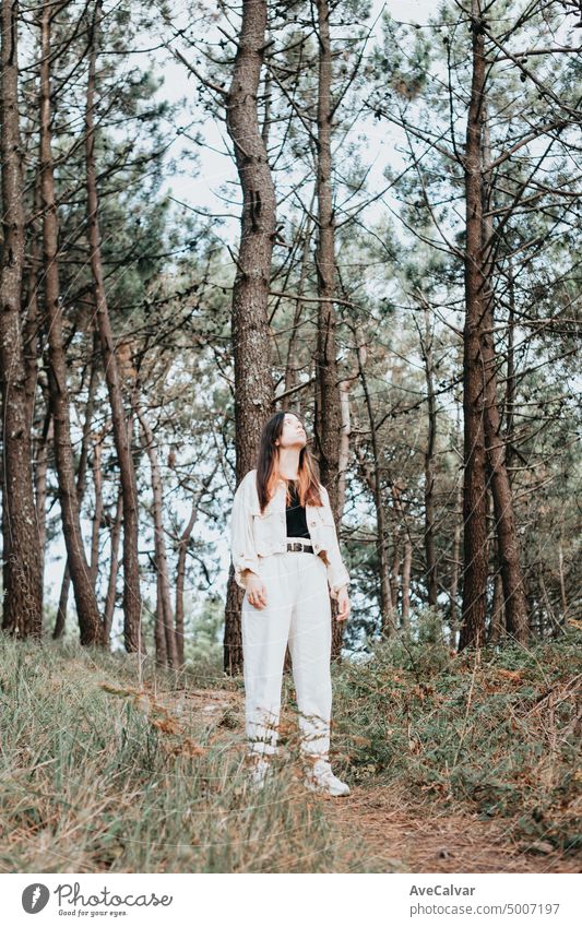 Happy woman in forest with open arms from behind breathing clean air. Environment, no pollution healthy natural living lifestyle. Nature is where she loves to wonder.Free spirit in the woods.