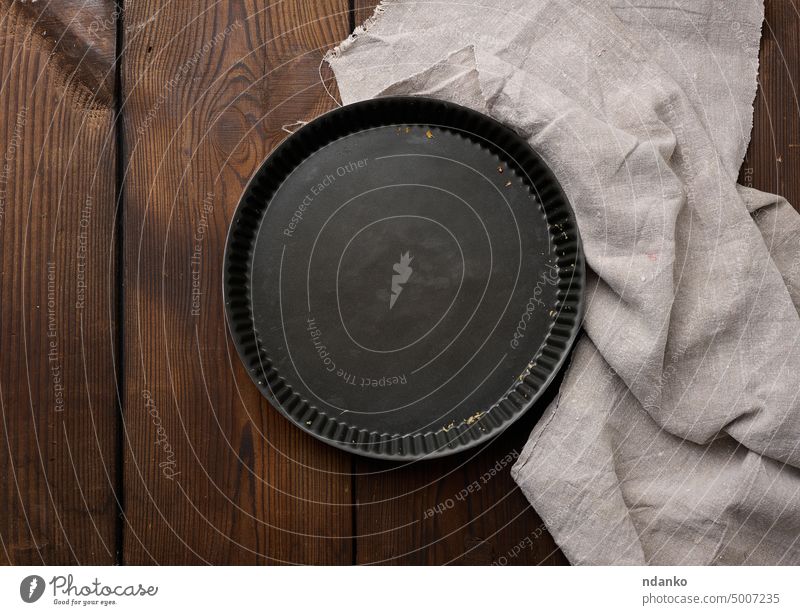 Empty black round non-stick cake pan on a brown wooden table oven pastry pie steel tool top traditional tray utensil napkin bake circle clean cooking dessert