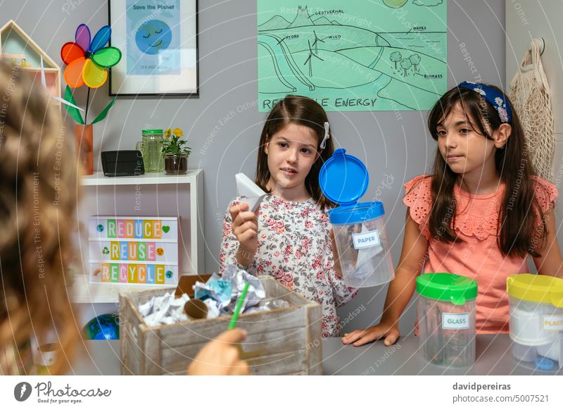 Student explaining how to recycle cardboard while holding sorting waste bin girl student teacher paper ecology showing selective ask classroom teaching glass