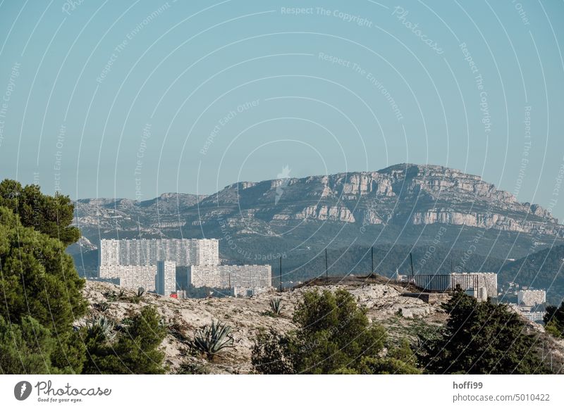 a very large isolated apartment block on a hill in front of a mountain with blue sky block of flats Deprived area High-rise mass accommodation Building