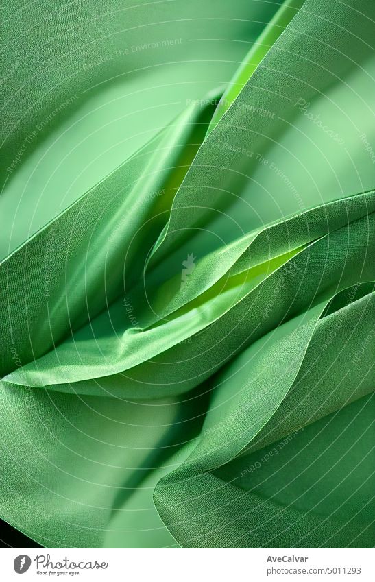 Green background. Folds on shiny fabric surface. Beautiful dark background curtain curve drapery elegant flowing luxury material smooth soft textile wave wavy