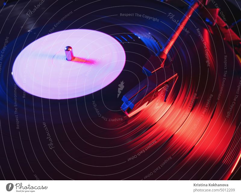 Phono or capsule head of reading an LP turntable spinning. Close up of turntable vinyl stylus going down. Playing the beginning of a black 33 rpm record on player.