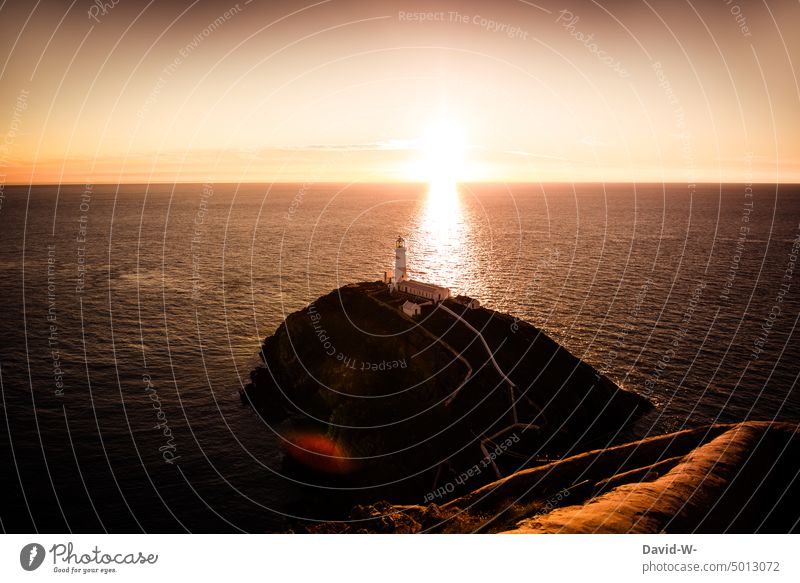 Lighthouse on the horizon illuminated by the setting sun Sunset Ocean beautifully Sunbeam golden Sunlight Vacation mood coast Vacation & Travel