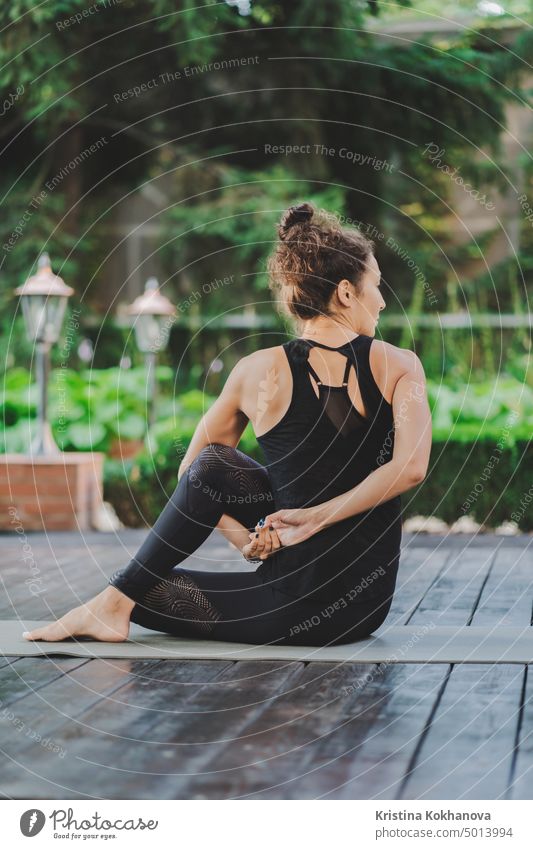 Young woman with oriental appearance practicing yoga alone on wooden deck in tropical island. Sport, fitness, healthy lifestyle concept nature workout balance