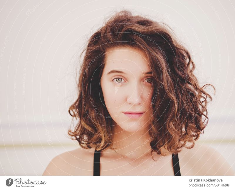 Portrait of young pretty yoga girl with short curly hair in sportswear. Calm and peace on her face. Slight smile. Film toned filter. woman person beauty model