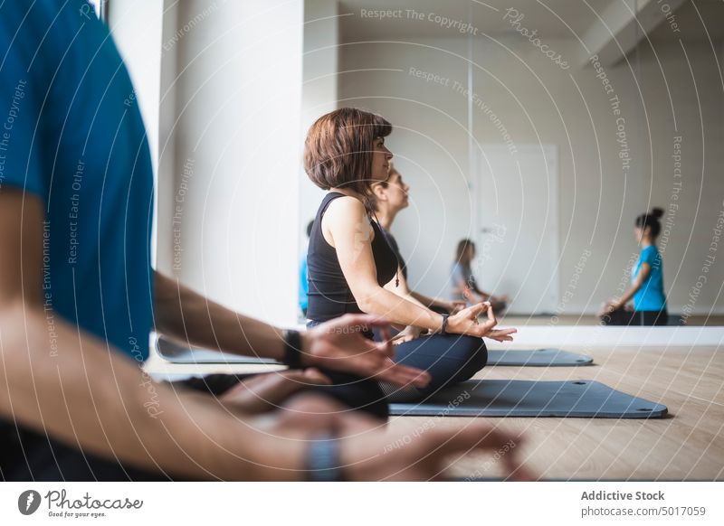 Group of people with instructor practicing yoga in studio meditate lotus pose padmasana group practice class together trainer vitality balance healthy wellbeing