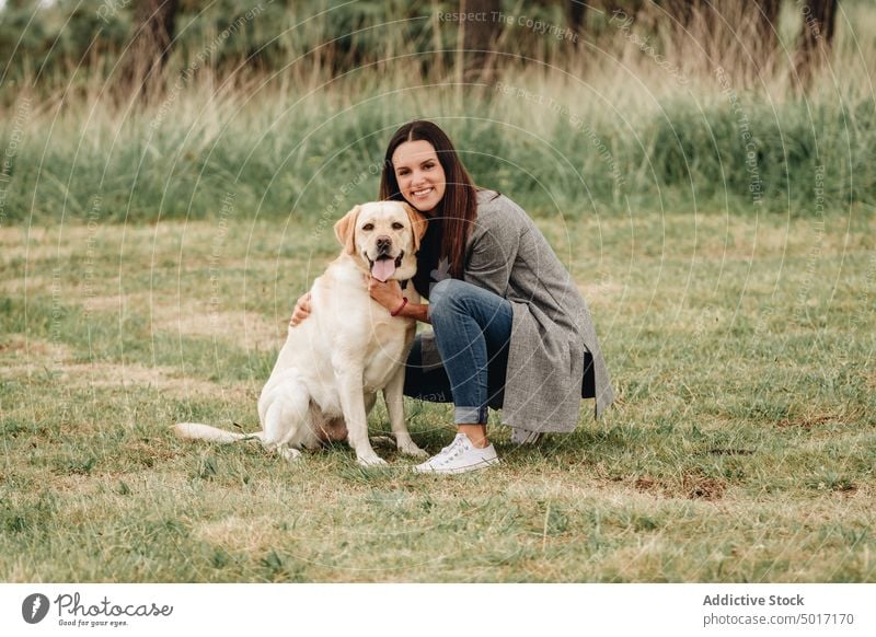 Woman hugging cheerful dog sitting on grass woman park fun happy pet nature green animal labrador retriever joyful together friendship companionship beautiful