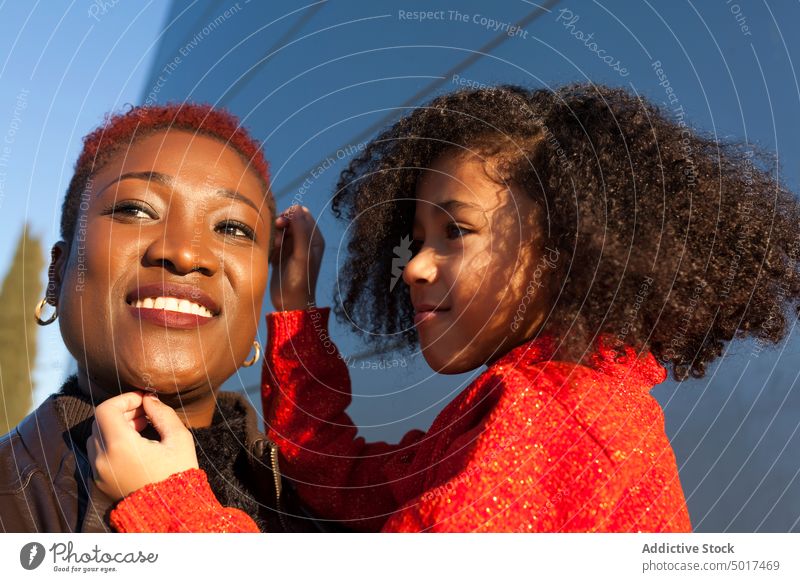 Smiling cute black girl holding black child on street mother step sunshine woman smiling cheerful daughter stair sunny day african american happy positive walk