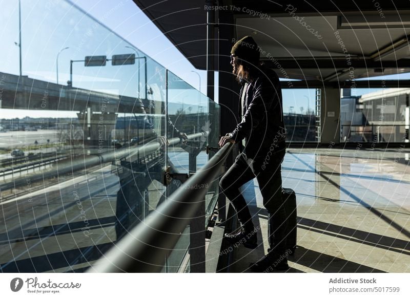 Hipster man with luggage in airport travel passenger suitcase wait treadmill trendy style hipster modern black baggage male hat leather jacket trip journey