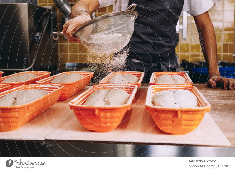 Crop male baker sprinkling flour on dough sprinkle man cook process scatter bread prepare apron raw bakery food kitchen chef cuisine fresh culinary pastry meal