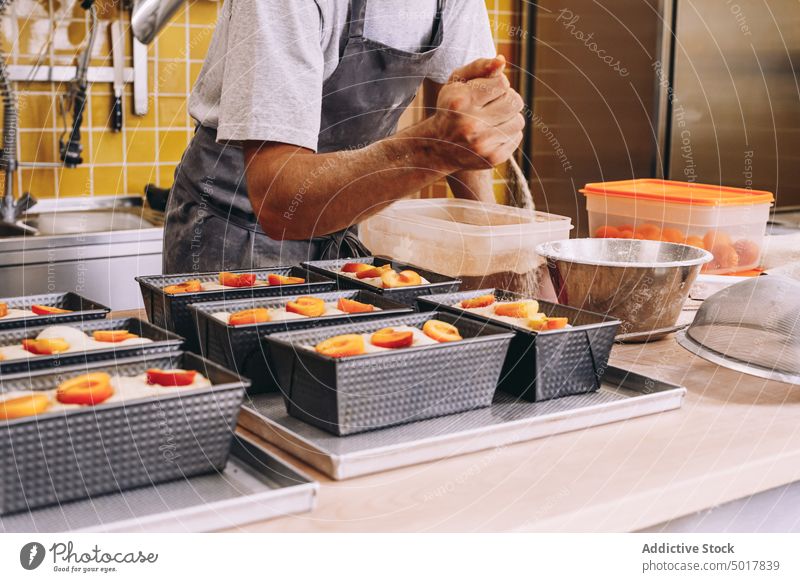 Crop male cook sprinkling dough with sugar sprinkle baker man scatter sweet kitchen process bakery cuisine apron bread food prepare delicious dish chef culinary