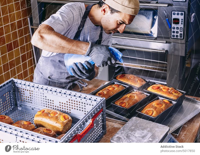 Man cook spraying raw dough with water baker bread process man bakery sprinkle kitchen male apron prepare cuisine ingredient culinary chef fresh food pastry guy