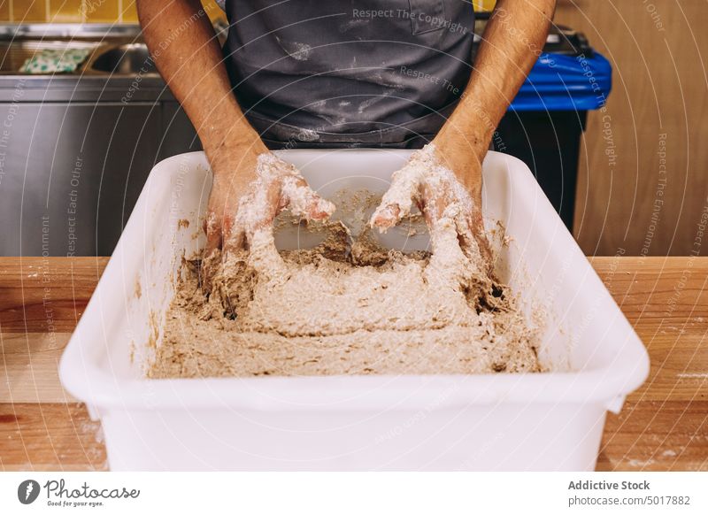 Anonymous man preparing dough in bakery kitchen work knead prepare professional process manual male young worker occupation employee bakehouse pastry handmade