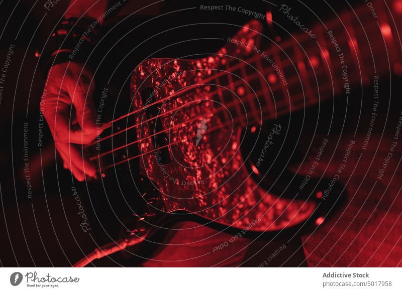 Close up of man playing guitar music guitarist bass player band anonymous hand rehearsing faceless rehearsal room studio redness guy instrument smiling neon