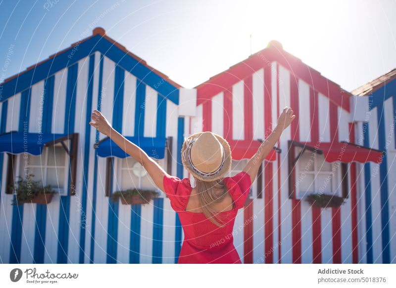 Anonymous traveler admiring bright building facades in summer city contemplate architecture house creative design street town woman walk pavement feminine dress