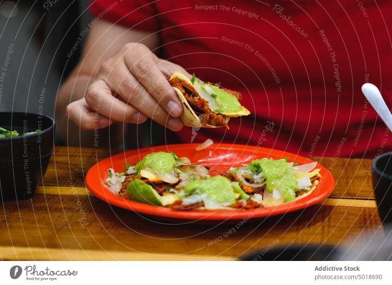 Crop person eating delicious taco at table street food mexican food lunch meal dish dinner restaurant tortilla culture tradition glass beverage refreshment