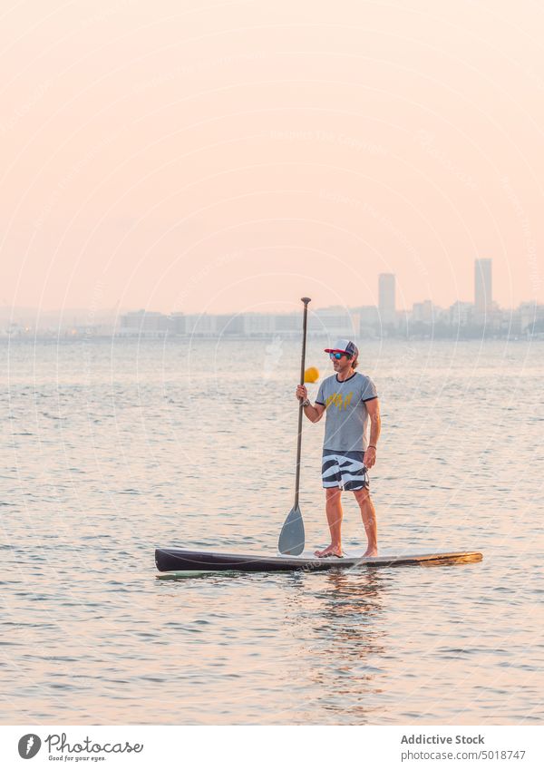 Man with paddle on surfboard on high seas man surfing ocean water active vacation summer male lifestyle extreme wave adventure recreation athlete summertime